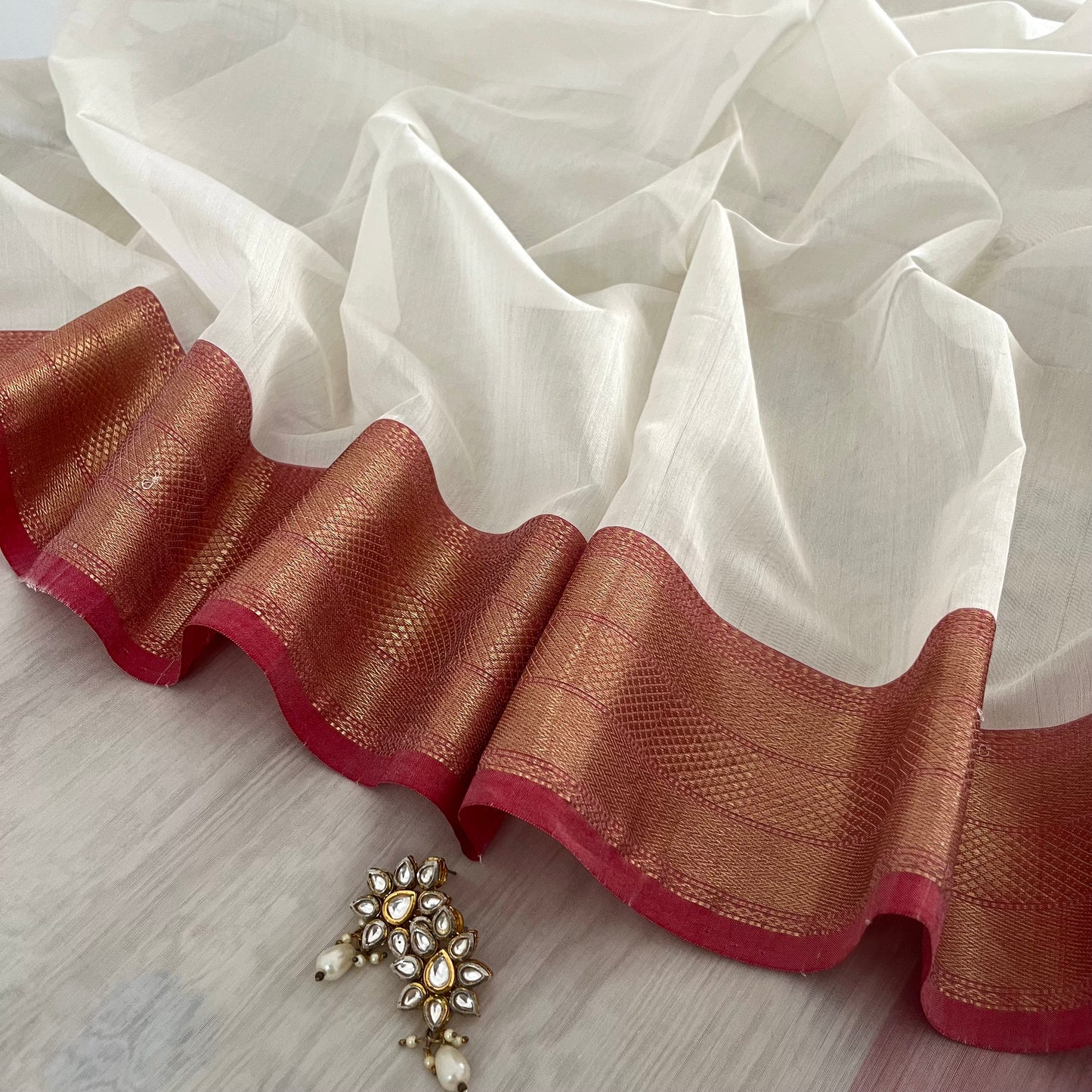 White and red Maheshwari saree with zari lines on pallu